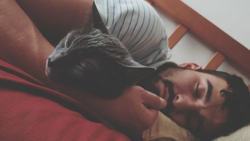 Close-up of man sleeping with cat on bed at home