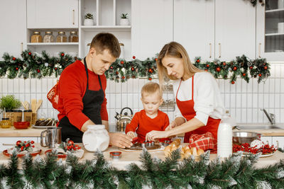 Happy family are concentrated on cooking christmas bisquits in the kitchen. 