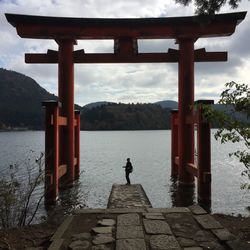 Man standing on riverbank against sky