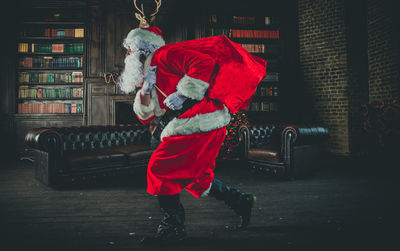 Side view full length of man wearing santa claus costume walking at home