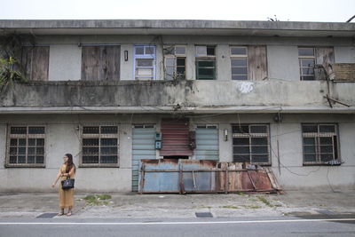 Full length of woman on road by building