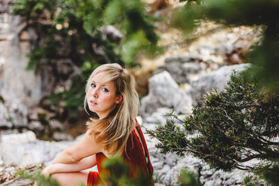 Portrait of woman sitting by tree