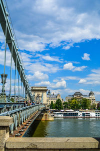 Bridge over river against cloudy sky