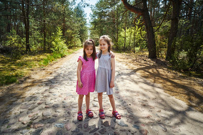 Full length of siblings standing on road amidst trees