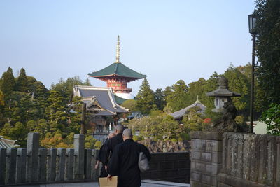 Rear view of monks walking against temple