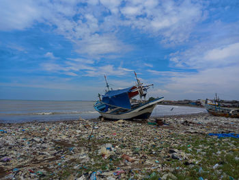 Boat moored on beach against sky