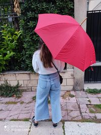 Man holding umbrella standing on footpath during rainy season