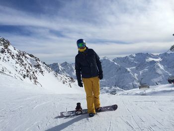 Full length of person with ski on snowfield against cloudy sky