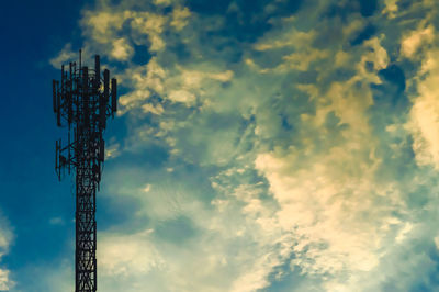 Low angle view of communications tower against cloudy sky