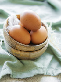 Bowl of fresh brown eggs on concrete background
