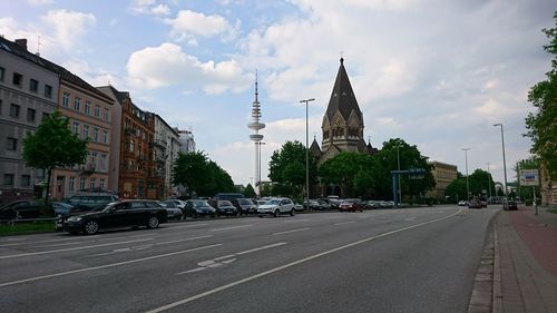 Cars on road in city against sky