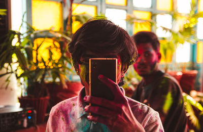 Portrait of young man photographing with mobile phone