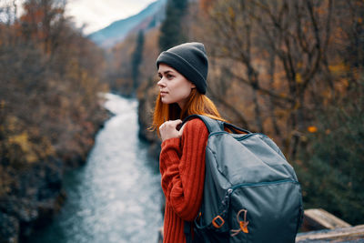 Young woman looking away while standing by tree during winter