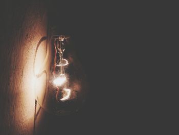 Close-up of illuminated light bulb against black background