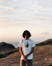 Rear view of man standing on mountain against sky