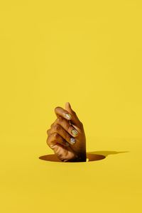Close-up of person hand against yellow background