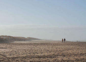 Rear view of people walking in desert against sky