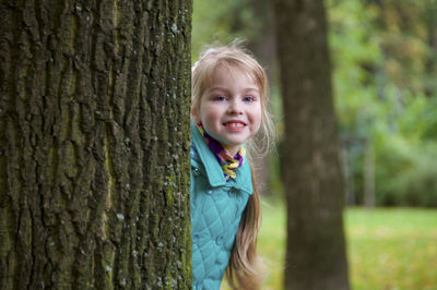 Portrait of cute boy against tree trunk