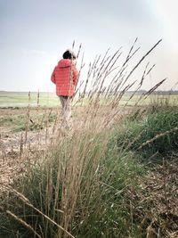 Rear view of boy wearing warm clothing while walking on land against sky