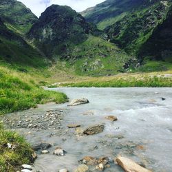 Scenic view of river by mountains against sky