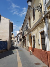 Empty road amidst buildings in city against sky