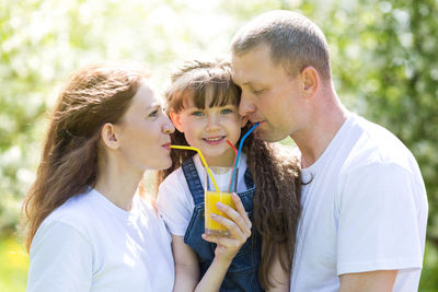 Parents with daughter drinking juice in park