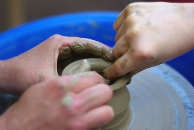 Cropped hands of people making clay pot