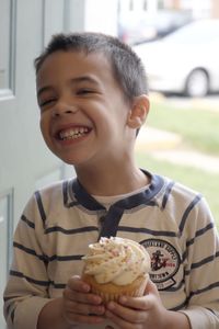 Happy boy holding cupcake while standing at doorway