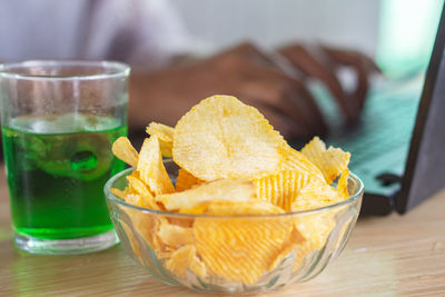 Woman eating potato chips with soda glass at work