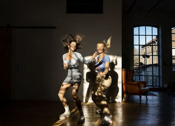 Happy friends dancing and playing air guitar at home