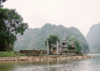 Picturesque scenery of ancient stone temple with green plants on shore of calm lake in thailand