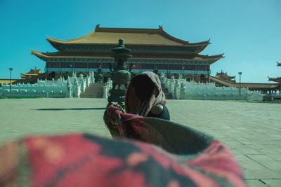 Rear view of woman at temple against clear sky