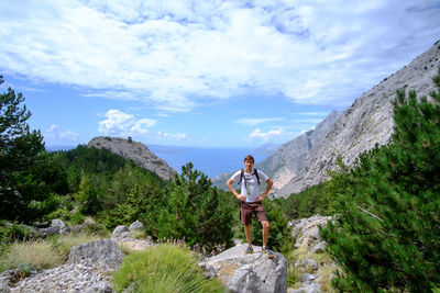 Woman standing on rock against sky