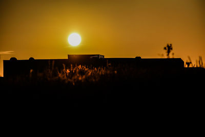 Scenic view of silhouette field against orange sky