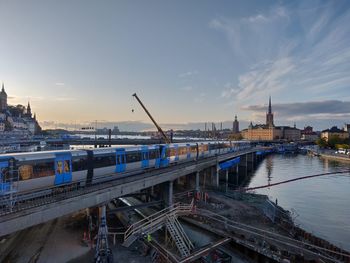 Bridge over river in city against sky during sunset