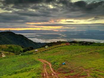 Scenic view of grassy field against cloudy sky