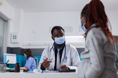 Doctor wearing mask talking with pregnant woman