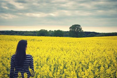 Rear view of woman standing field against sky