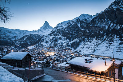 Snow covered houses and mountains against sky