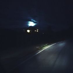 Illuminated road against sky at night