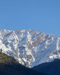 Close up of snow peak mountain range glowing in sunlight with clear blue sky