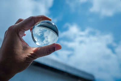 Midsection of person holding glass against sky