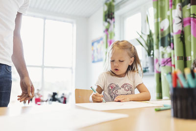 Female student drawing at table in classroom