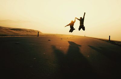 Silhouette man jumping on landscape against sky