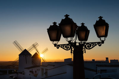 Low angle view of street light and building against sky during sunset