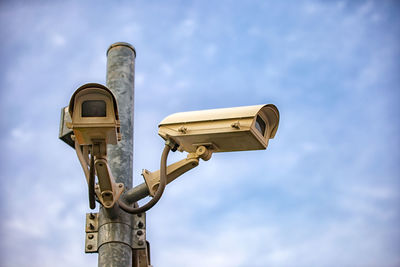 Close-up of security camera on pole against sky