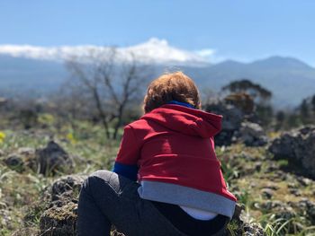 Rear view of woman sitting on rock