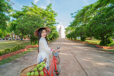 Portrait of smiling woman with bicycle on road