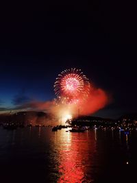 Firework display over illuminated vancouver against sky at night