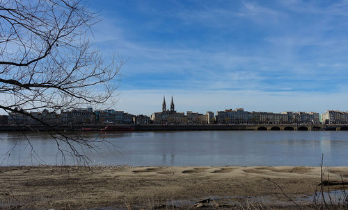City at waterfront against cloudy sky